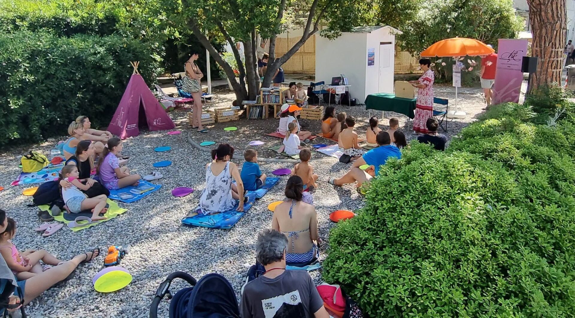 Otroci poslušajo pravljico na plaži v Sesljanu.
