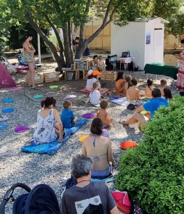 Otroci poslušajo pravljico na plaži v Sesljanu.