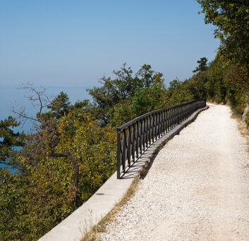 An elevated sun-drenched trail facing the ble sea. Taken on the via Napoleonica in Trieste, Italy