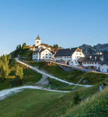 Small and ancient village of Lussari or Monte Santo di Lussari (1790 m) and the peak of Mangart mountain (2677 m.). Julian Alps, Tarvisio, Udine province, Friuli Venezia Giulia, Italy, Europe.