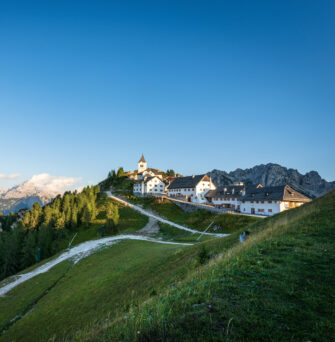 Small and ancient village of Lussari or Monte Santo di Lussari (1790 m) and the peak of Mangart mountain (2677 m.). Julian Alps, Tarvisio, Udine province, Friuli Venezia Giulia, Italy, Europe.