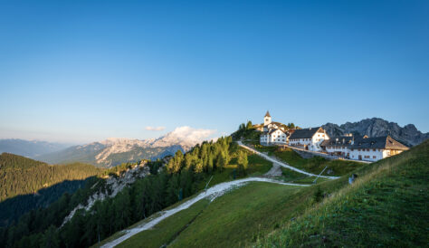 Small and ancient village of Lussari or Monte Santo di Lussari (1790 m) and the peak of Mangart mountain (2677 m.). Julian Alps, Tarvisio, Udine province, Friuli Venezia Giulia, Italy, Europe.